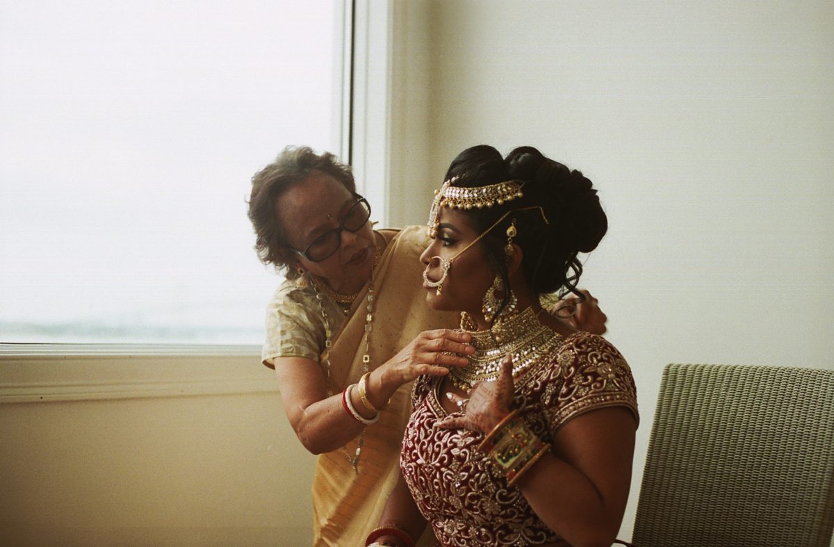 Mother helping bride with necklace